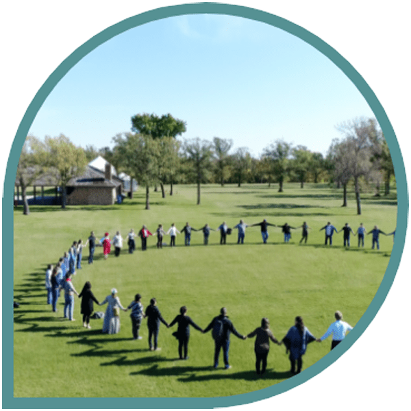 a large circle of people holding hands outdoors