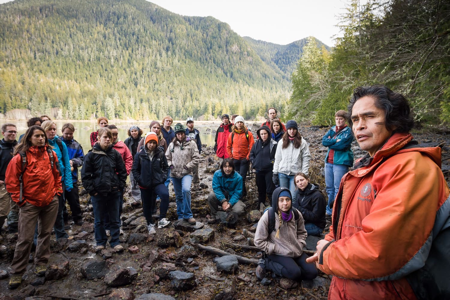 Large group of people standing in a ravine between treed mountains on Meares Island