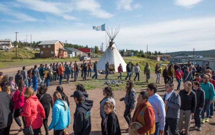 Members of the Łutsël K’é Dene First Nation celebrate the creation of the Thaidene Nëné Indigenous Protected Area in August 2019. People are dancing in a circle around a fire to the drum with a tipi in the background.