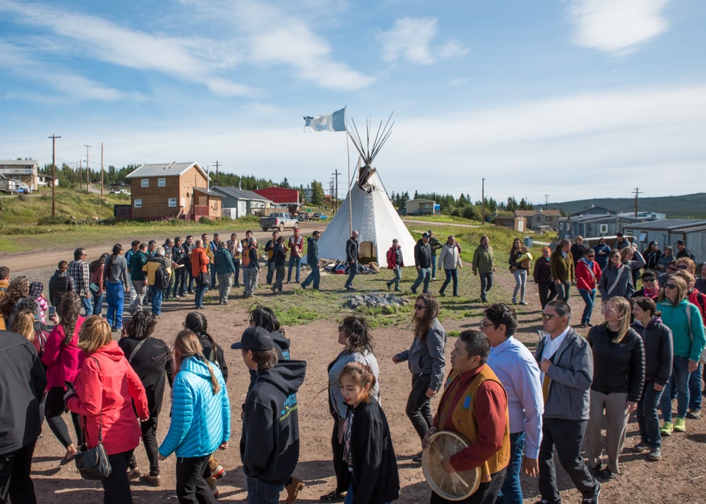 Members of the Łutsël K’é Dene First Nation celebrate the creation of the Thaidene Nëné Indigenous Protected Area in August 2019. People are dancing in a circle around a fire to the drum with a tipi in the background.