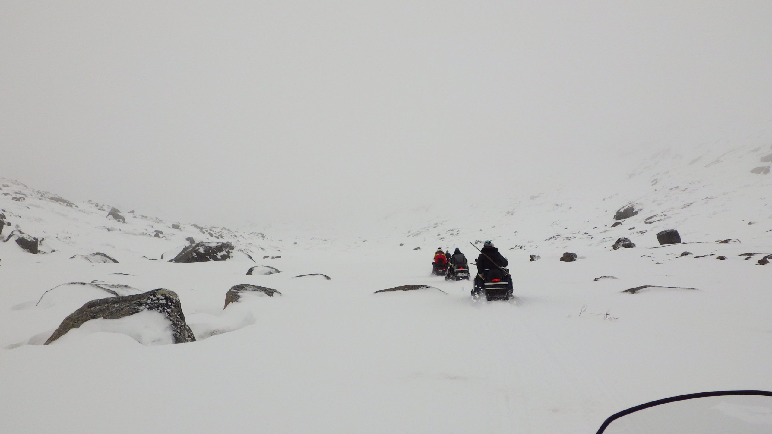 A group of people riding snowmobiles on a wintery day