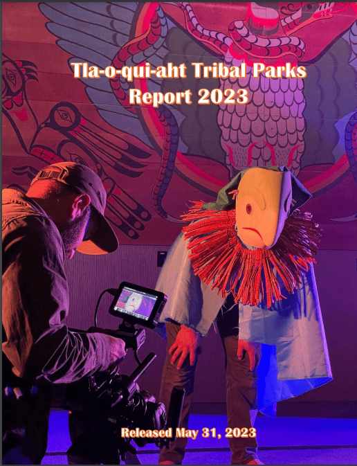 The cover image for the Tla-o-qui-aht Tribal Parks annual report. A man records a figure in traditional regalia with a cell phone.